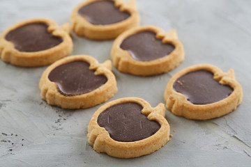 Apple shaped biscuits arranged in rows on light textured background, close-up, shallow depth of field, selective focus.