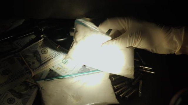 Criminalist in gloves finds a cache with weapons, drugs and money. Search and criminal investigation concept