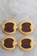 Apple shaped biscuits arranged in rows on light textured background, close-up, shallow depth of field, selective focus.