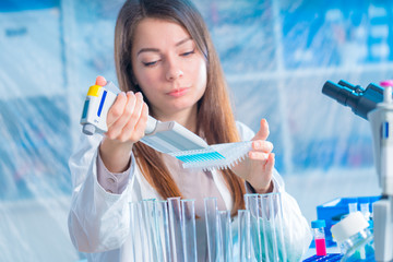 student woman with multi pipette and other PCR items in microbiological / genetic laboratory
