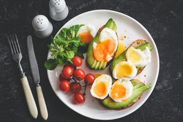 Poached egg and avocado toasts on white plate, top view, toned image. Healthy breakfast or lunch