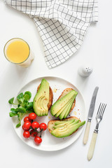 Fototapeta na wymiar Avocado toasts and orange juice on white background, top view. Concept of healthy breakfast, healthy lifestyle, dieting, fitness, weight loss, vegan, vegetarian