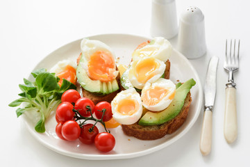 Egg and avocado toasts on white plate, closeup view. Concept of healthy breakfast, healthy lifestyle, dieting, fitness, weight loss, vegan, vegetarian