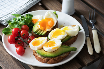 Egg and avocado, green salad and cherry tomatoes on white plate. Healthy breakfast, healthy lifestyle, vegan, vegetarian diet or weight loss concept