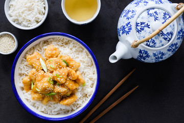Chicken with rice, sesame seeds and green tea on black stone background, top view. Chinese cuisine