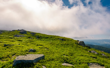 grassy meadow with boulders under the huge cloud. beautiful landscape on fresh summer morning