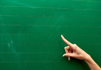 Right hand of a young girl pointing at the center of a green school board