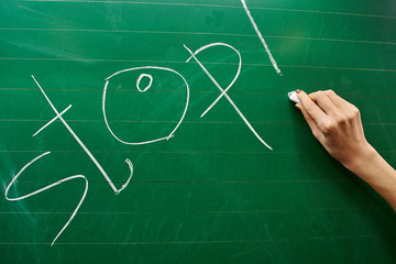 Hand of a young girl writing the word STOP on the green school board