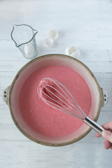 pink cake mix in bowl with eggs top view on clean white background