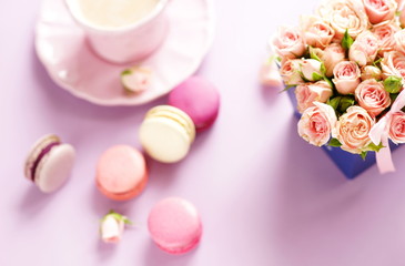 Obraz na płótnie Canvas Blur effect macaroons in pastel colors with bouquet of pink roses flowers on a pale purple background.Holiday background.copy space.top view