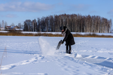 Fototapeta na wymiar young woman in black coat cleaning ice from snow