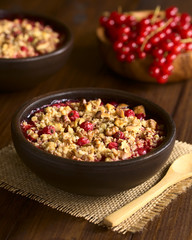 Redcurrant crumble or crisp with oatmeal and walnut on top baked in rustic bowl, photographed on dark wood with natural light (Selective Focus, Focus in the middle of the crumble)
