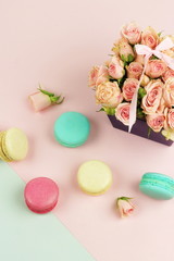 macaroons in pastel colors with bouquet pink roses  flowers on a pale pink background.Holiday background.copy space.