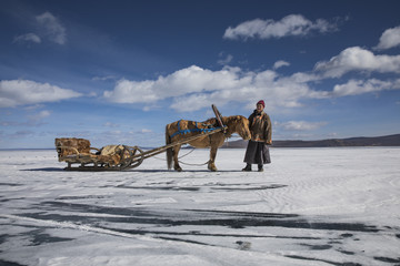 mongolian man with his horse sledge on frozen lake Khovsgol