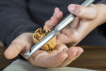 Manos de una persona cascando nueces con un cascanueces