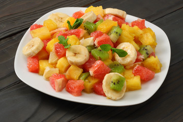 Bowl of healthy citrus fruit salad on dark wooden background. Top view.