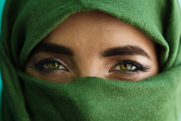 close up of green eyes of a girl with face wrapped in a green scarf