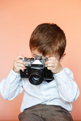 Little boy with aged retro camera. Child with an old camera