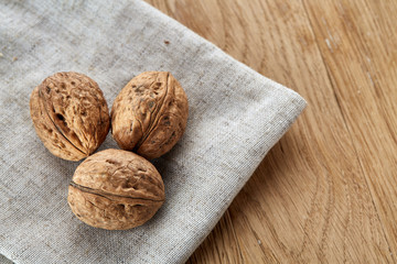 A stack of hard shells of walnuts piled together on light grey fabric cotton tablecloth, selective focus