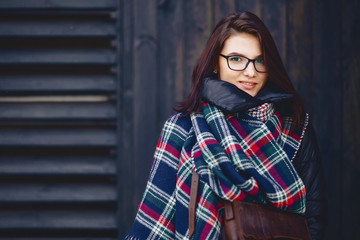 portrait of beautiful girl in eyeglasses and a scarf against a wooden wall