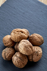 A stack of hard shells of walnuts piled together on light grey fabric cotton tablecloth, selective focus