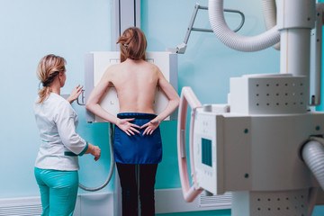 Radiologist and patient in a x-ray room. Classic ceiling-mounted x-ray system.