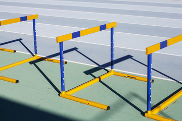 Naklejka premium Yellow blue jumping hurdles on running track
