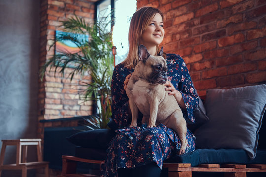 Portrait of a smiling woman sitting with a cute pug in a room wi