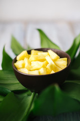 Sliced fresh pineapple in a bowl on the leaves