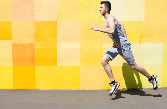 Side View Of Man Running Against Bright Wall