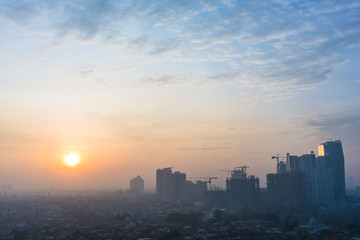 Panoramic view of Jakarta cityscape with skyscrapers and buildings under construction at sunrise