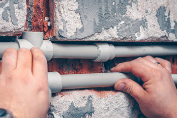 The worker carries out plumbing works in the house, mounts water pipes from polypropylene