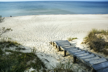Exit on a wooden ladder to the sea with snow-white sand