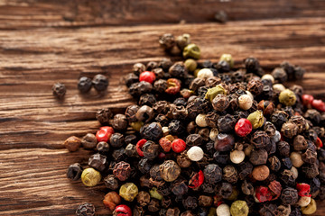 Top view on black, red and white peppercorns isolated on wooden background, shallow depth of field.