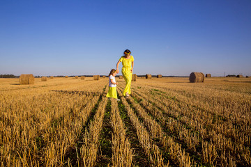 Mom and daughter in identical yellow dresses run across the fiel