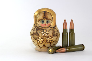 Russian matryoshka and several cartridges for a Kalashnikov assault rifle on a white background...