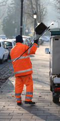 sweeper with an orange jacket collecting rubbish