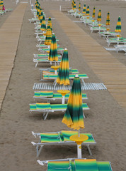 yellow and green loungers and umbrellas  along an Italian beach