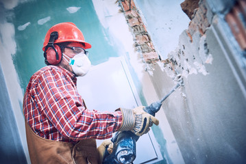 worker with demolition hammer breaking interior wall - obrazy, fototapety, plakaty
