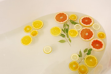 slices of citrus yellow lemon, orange and red grapefruit in the water of bath