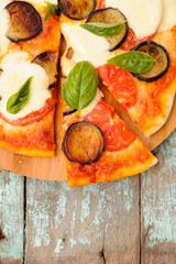 Healthy vegetarian pizza with eggplants, tomatoes, basil leaves and mozzarella on old wooden background copyspace