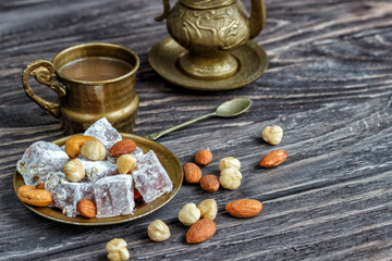 Oriental Arabian sweets with different nuts a cup of coffee. Eastern sweets. Traditional Turkish delight (Rahat lokum) on a wooden background. View from above.