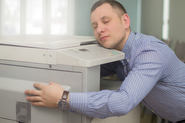 exhausted businessman or office manager sleeping on a multifunction printer or copier