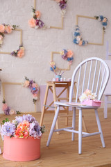 spring decorated studio with white chair easel and flower in the box. hello march, april, may
