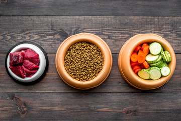 Ingredients for dry pet food. Meat and vegetables zucchini and carrot on dark wooden backgroud top view copy space