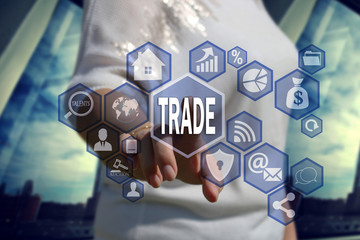 The businessman chooses  button  TRADE on the touch screen with a futuristic background .The concept TRADE