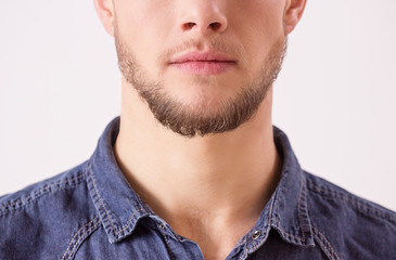 Close up of young unshaved man isolated over white background. Portrait of bearded hipster man's...