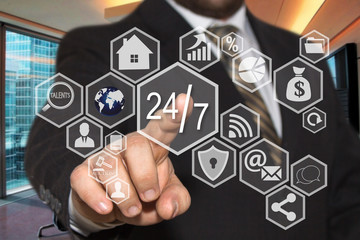 The businessman chooses  button  24 hours 7 days web service icon on the touch screen with a futuristic background .The concept  24 hours 7 days web service.