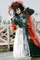 woman in beautiful red green and white masquerade  dress and mask at the Venice carnival Italy