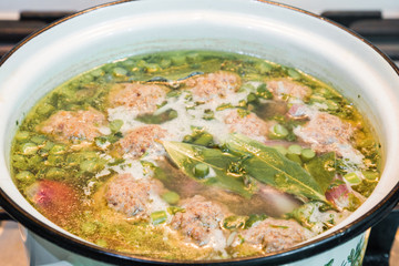 Homemade soup with meatballs in a saucepan. Closeup.
